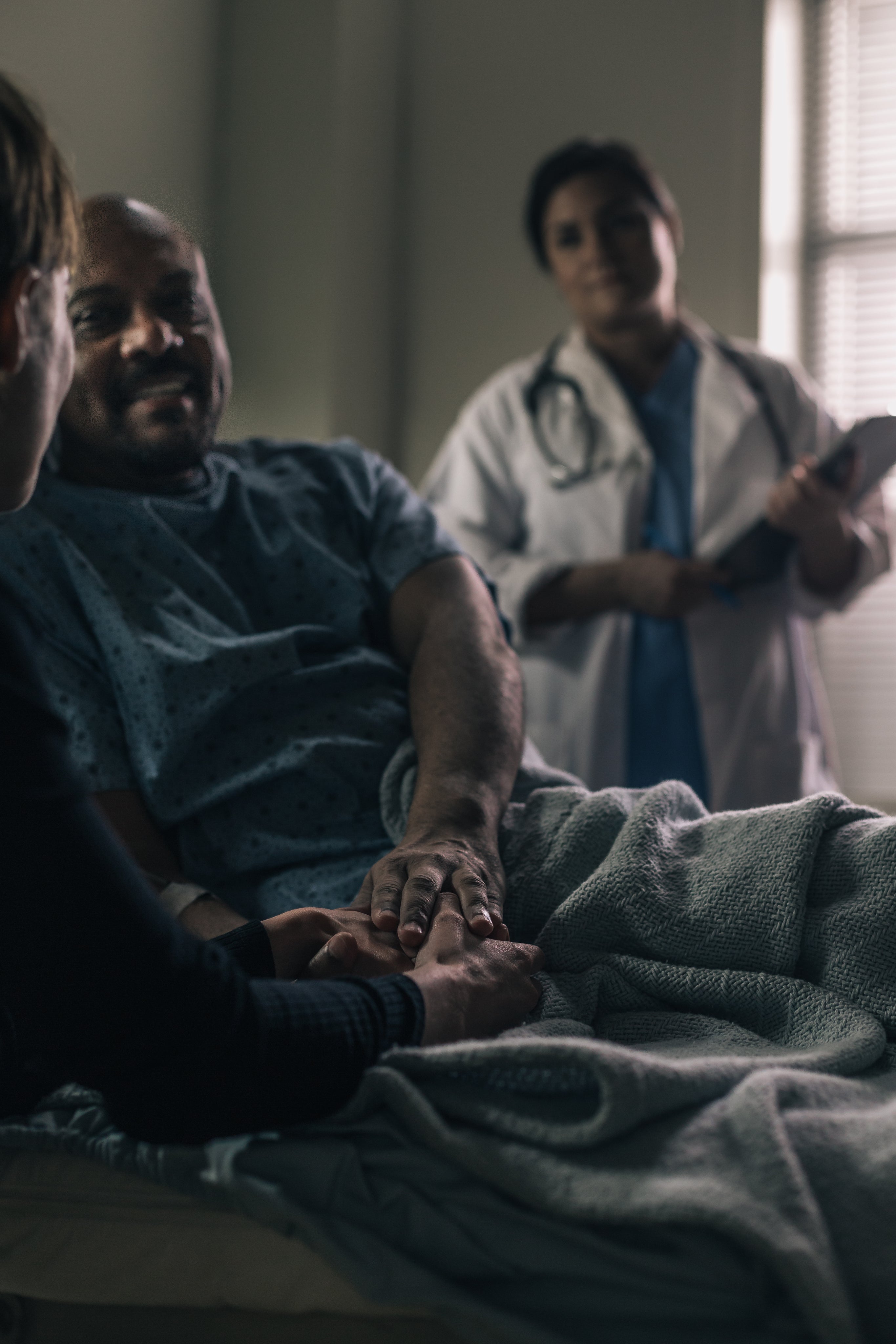 a-male-patient-smiles-while-holding-the-hand-of-a-friend.jpg